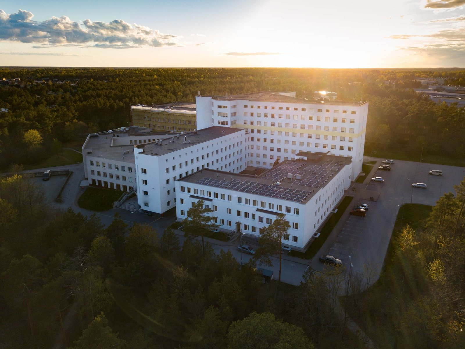 Aerial view of a large white hospital-style building complex at sunset